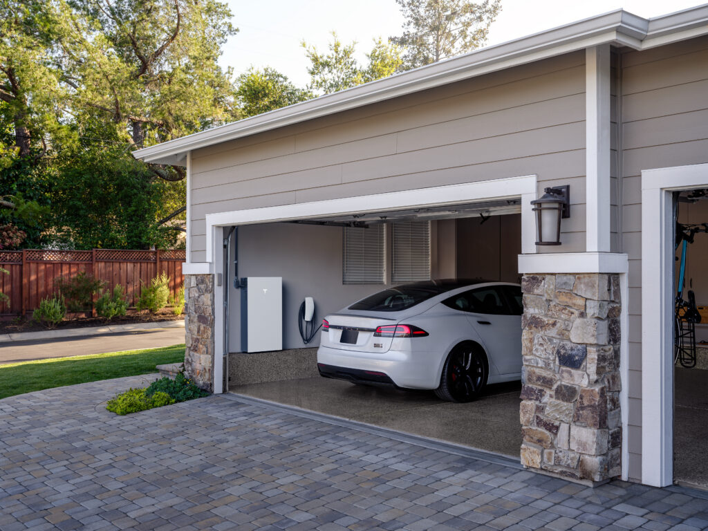 Tesla Powerwall 3 and Wall Connector mounted cleanly in a garage beside a Tesla